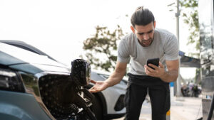 Man worryingly looking at his phone while checking EV battery